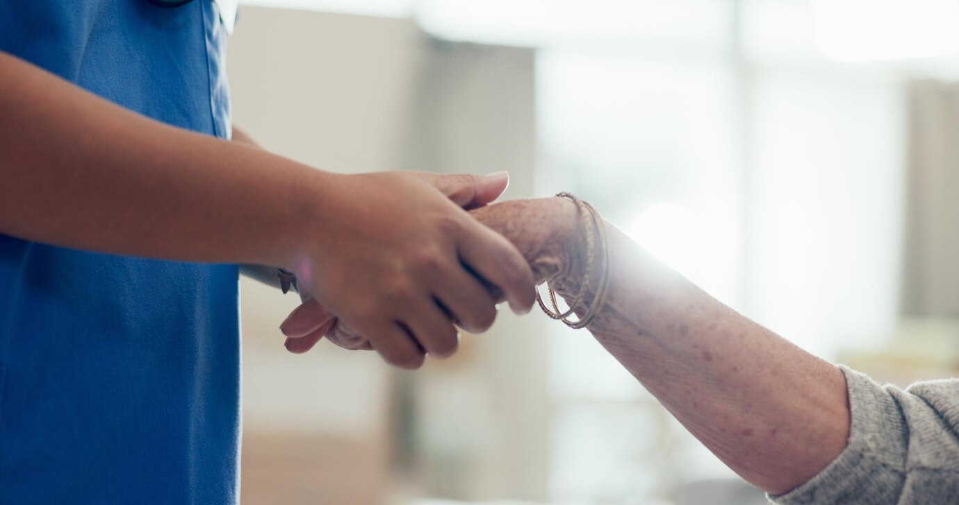 Manos de cuidador profesional sosteniendo la mano de persona mayor